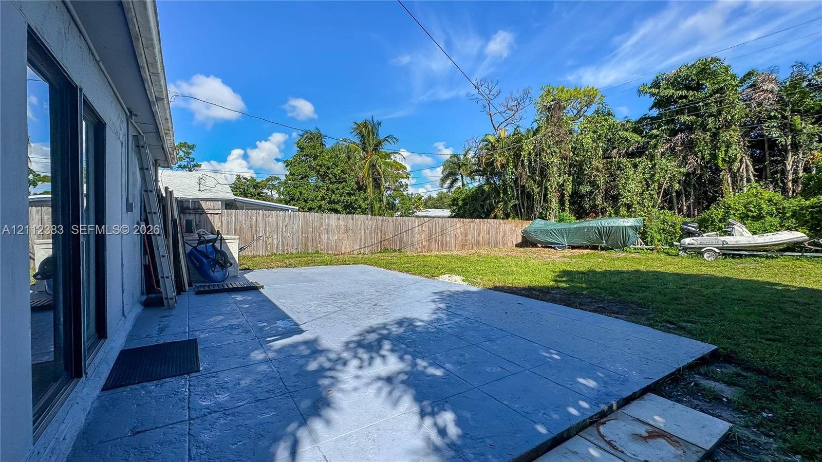 5319 Lake Boulevard, Delray Beach, Delray Beach, FL 33484 Concrete patio slab featuring a textured surface, enclosed by a wood perimeter fence, and accompanied by a grass lawn
