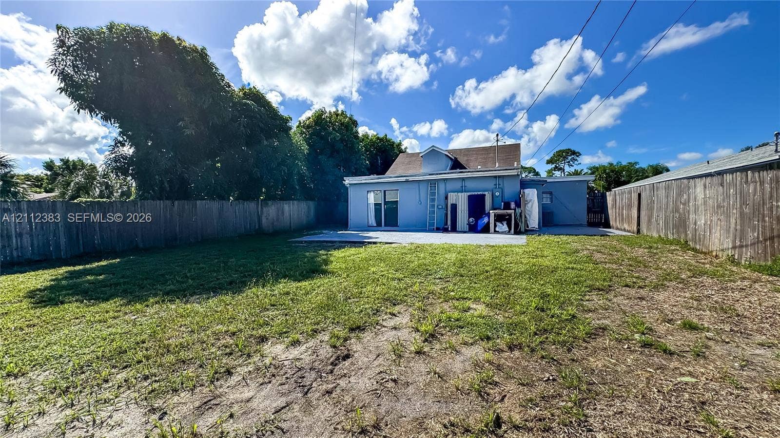 5319 Lake Boulevard, Delray Beach, Delray Beach, FL 33484 Fenced backyard featuring a concrete patio, grassy lawn, and perimeter wood fencing