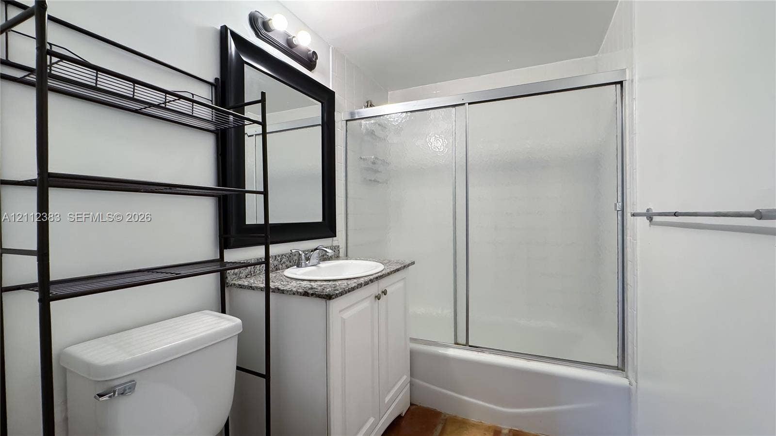 5319 Lake Boulevard, Delray Beach, Delray Beach, FL 33484 Bathroom featuring a white vanity with a stone-finish countertop, undermount sink, framed wall mirror, and a tub-shower combination with sliding glass doors