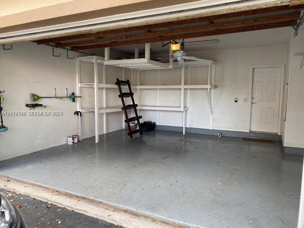 Garage featuring an epoxy-coated floor, integrated built-in shelving, overhead storage, and an exterior access door
