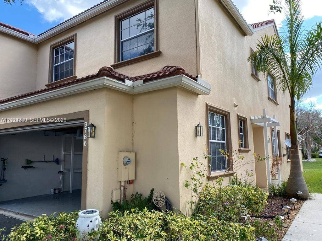 Stucco exterior featuring a clay tile roof, multi-pane windows, and an integrated garage