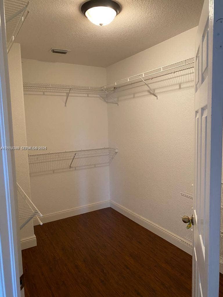 Storage space featuring white wire shelving and wood-finish flooring with a ceiling-mounted light fixture
