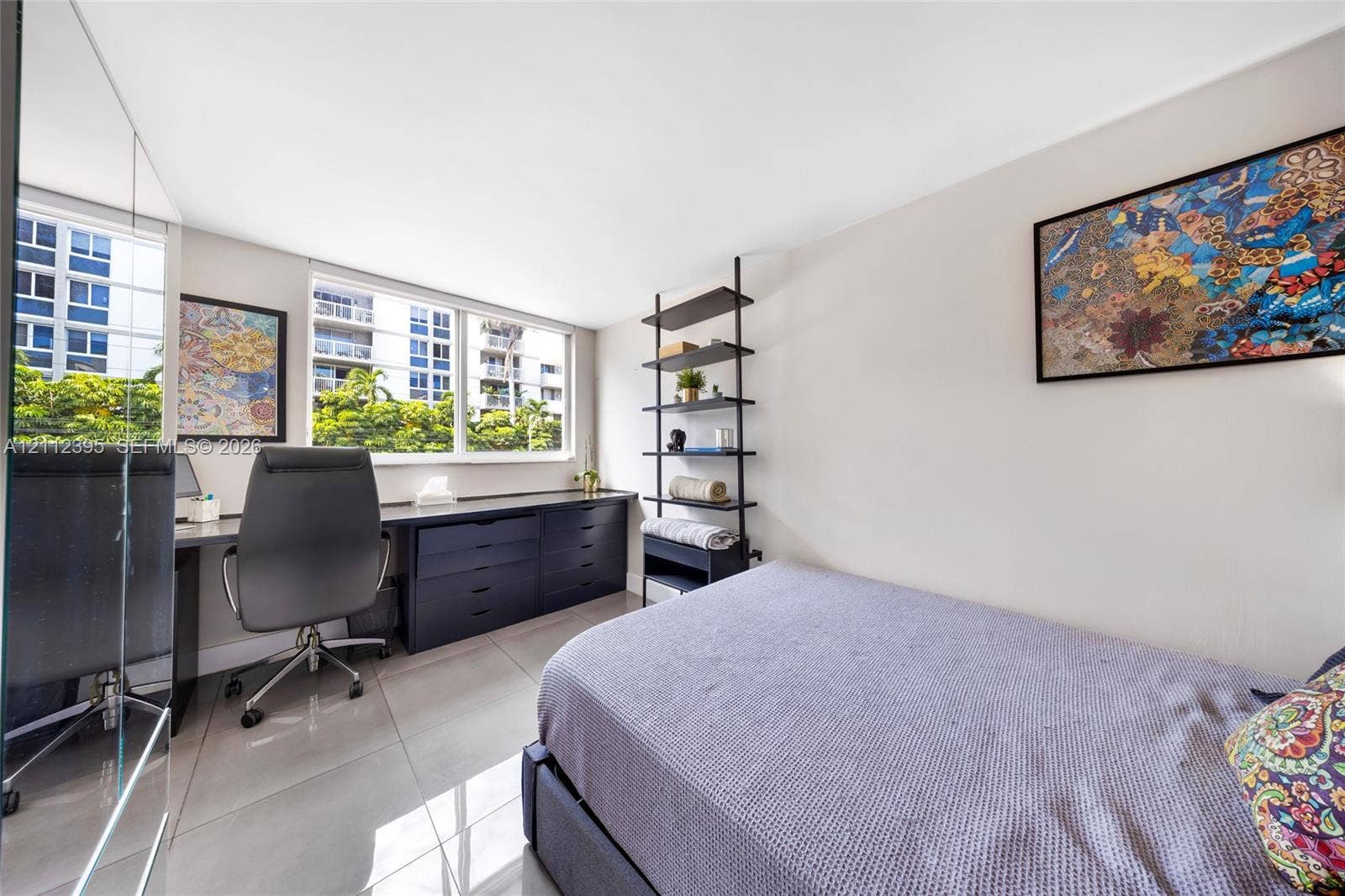 Interior room featuring large windows, neutral-toned tile flooring, and custom built-in cabinetry with a desk surface