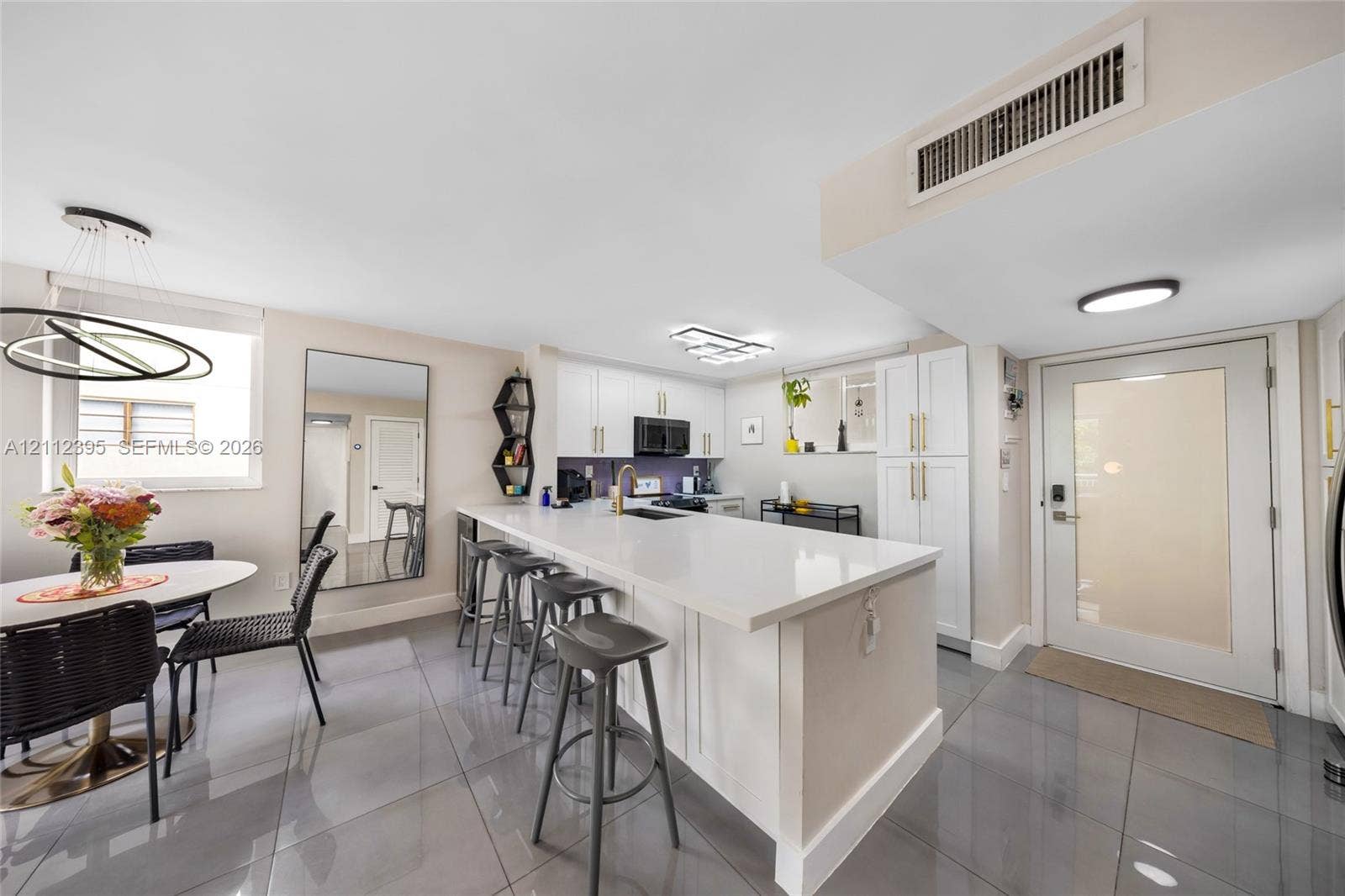 Kitchen featuring white cabinetry, solid-surface countertops, recessed lighting, and large-format tile flooring