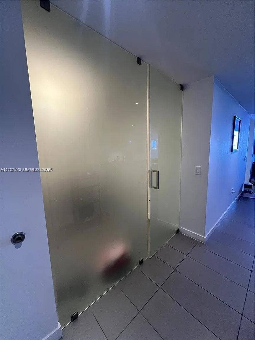 Frosted glass sliding doors with matte black hardware and large-format tile flooring