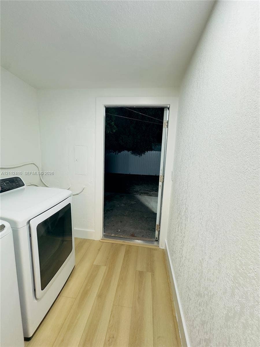 Utility space featuring wood-finish flooring, smooth-finish walls, and an exterior door