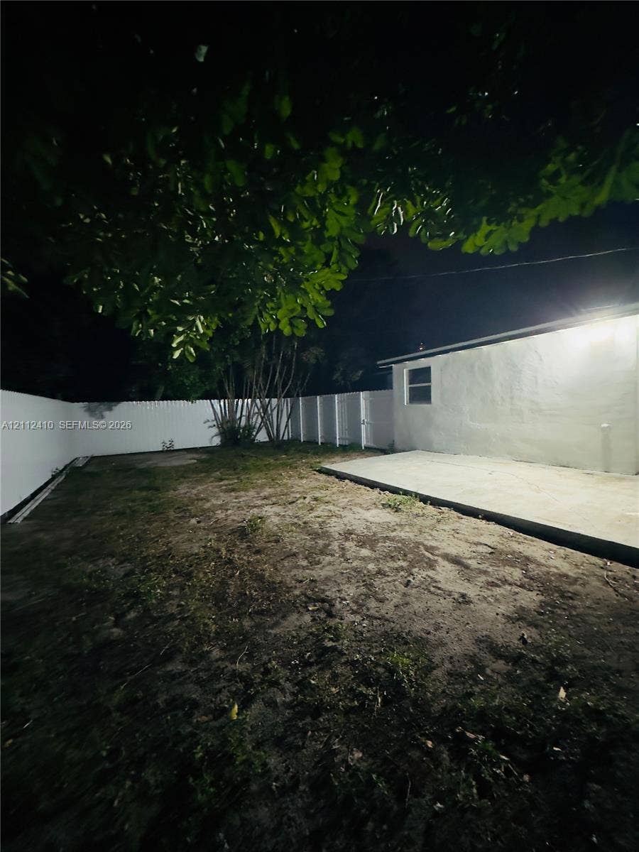 Backyard featuring a concrete patio, perimeter privacy fencing, and mature trees