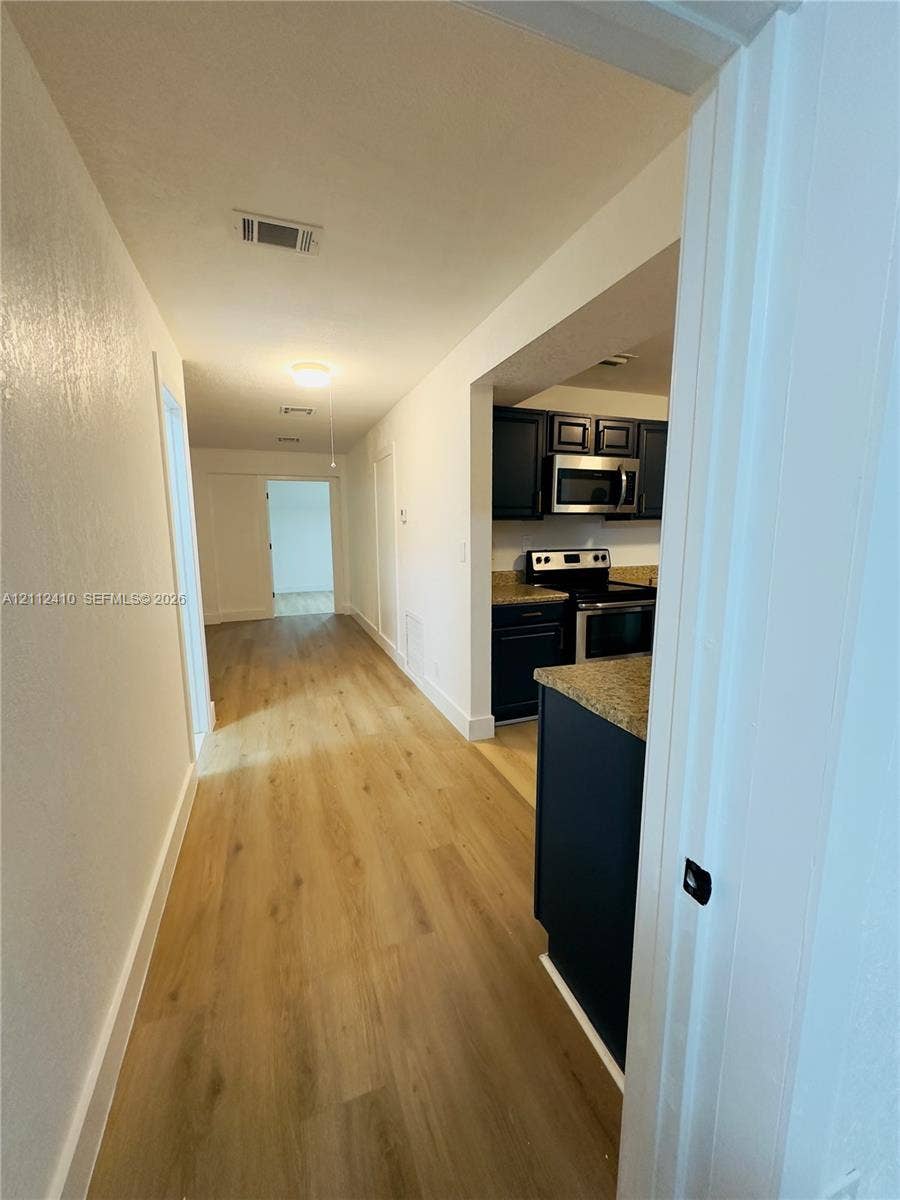 Wood-finish flooring, dark-toned cabinetry, and integrated stainless steel kitchen appliances