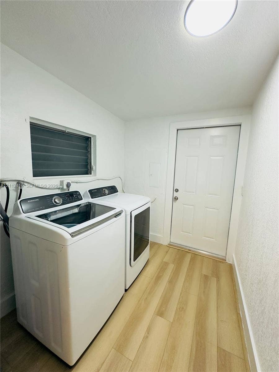 Utility room featuring wood-finish flooring, a jalousie-style window, and an exterior door with panel detailing