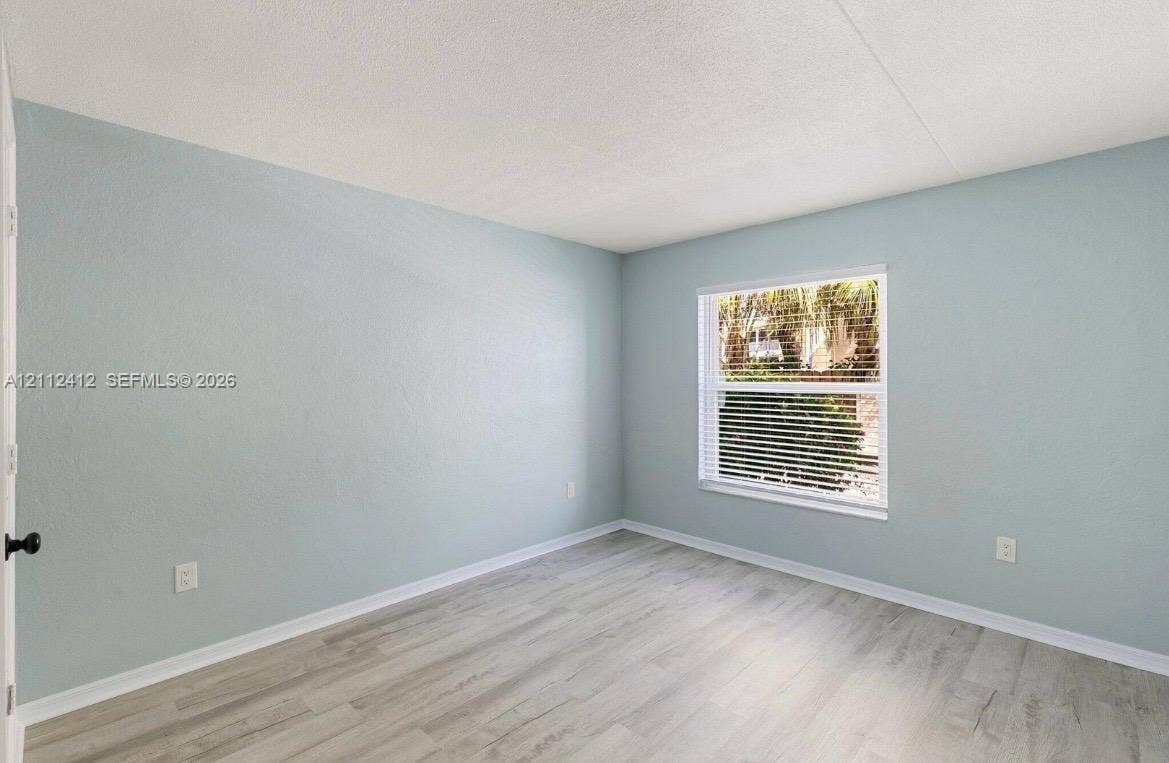 Neutral-toned wall paint, wood-finish flooring, and a single-pane window with adjustable horizontal blinds