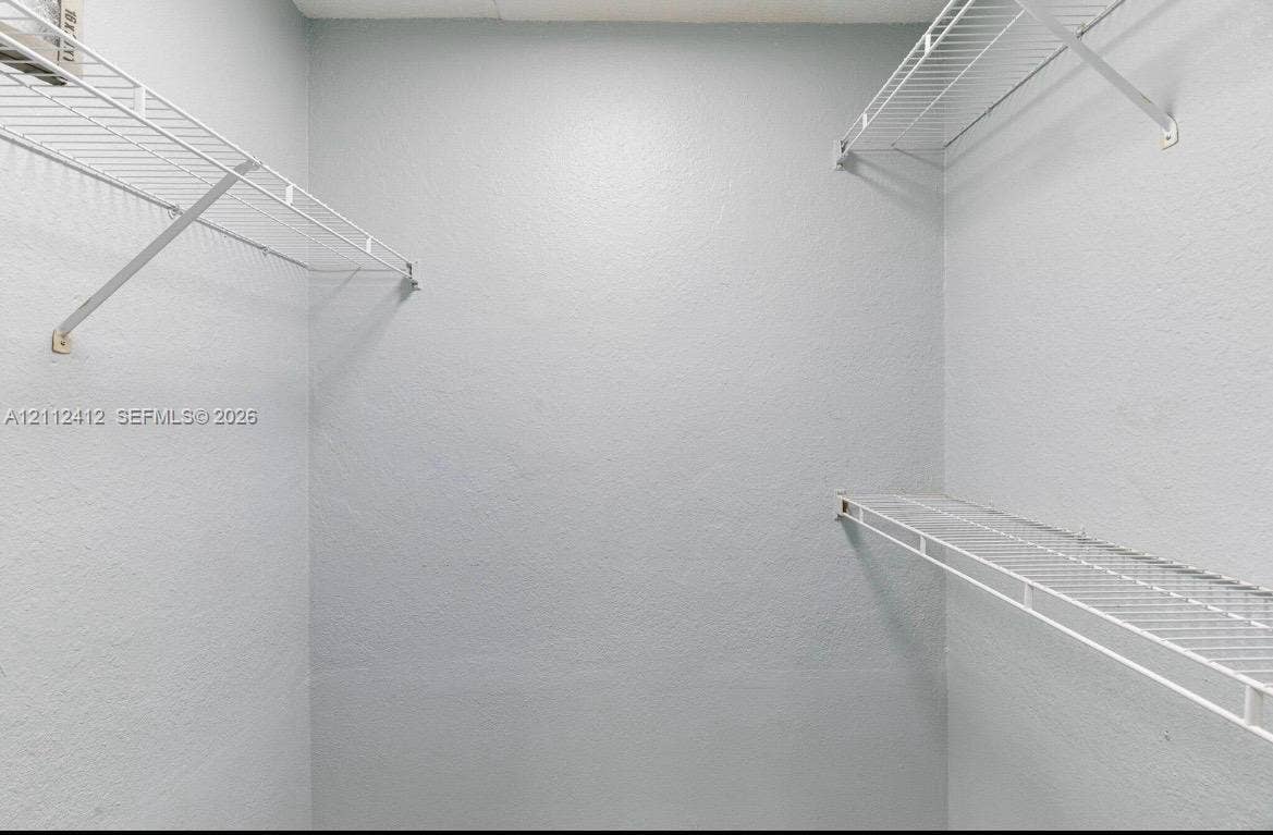 Storage space featuring white wire shelving units installed on three walls