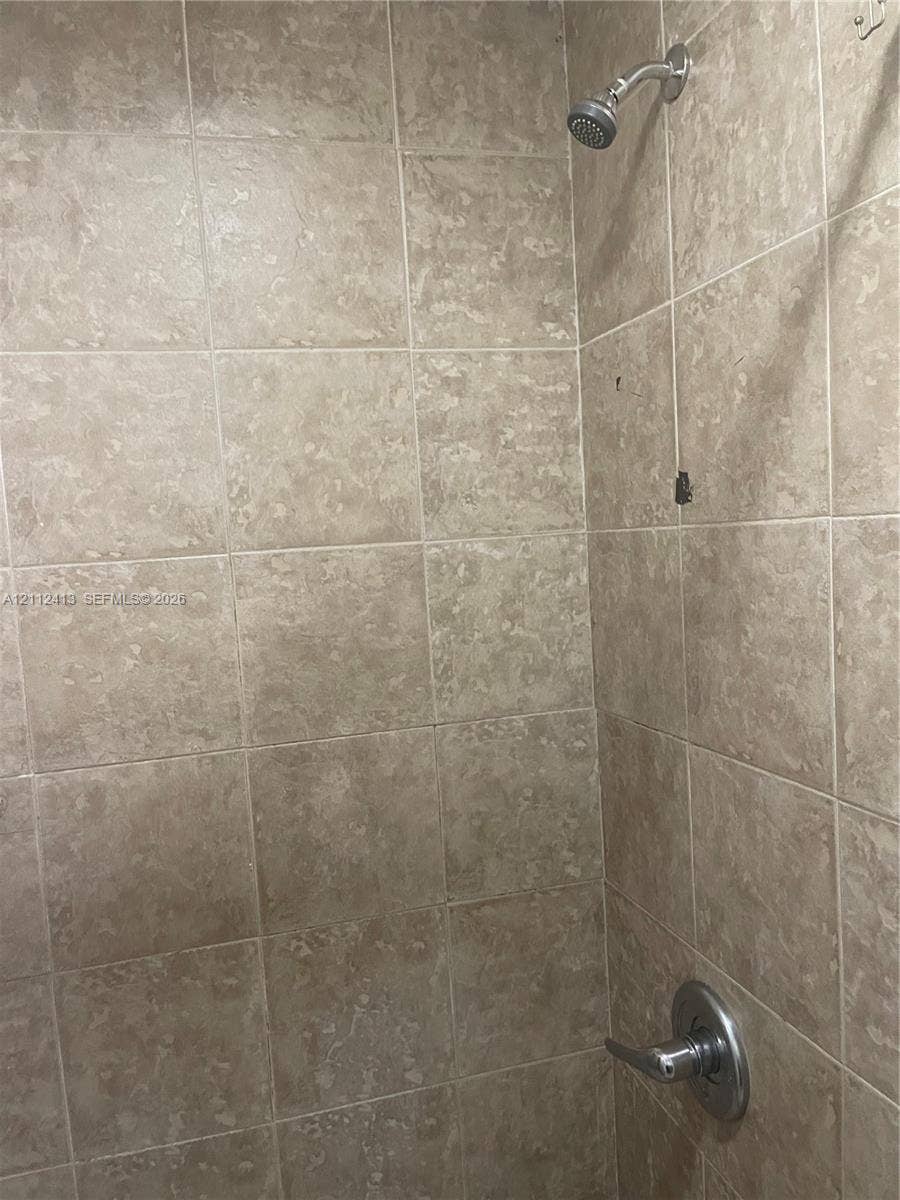 10830 Westwood Lake Drive, #0, Miami, Miami, FL 33165 Shower enclosure featuring neutral-toned wall tiles, a metallic single-handle pressure balance valve, and a wall-mounted shower head