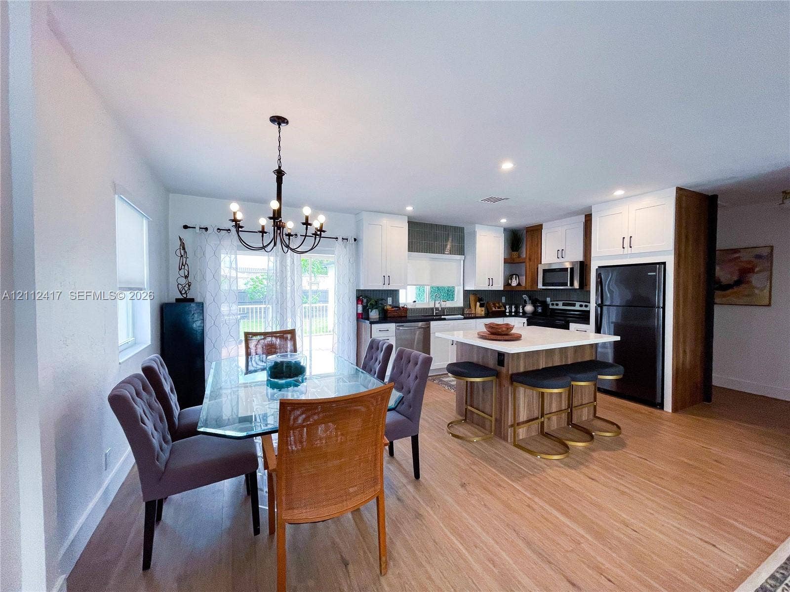 Kitchen featuring a center island with a stone countertop, white cabinetry, wood-finish flooring, and an overhead chandelier