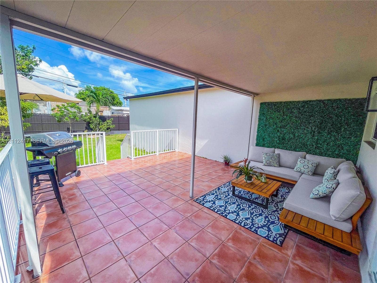 Covered patio featuring ceramic tile flooring, vertical garden wall, and white metal railing enclosure