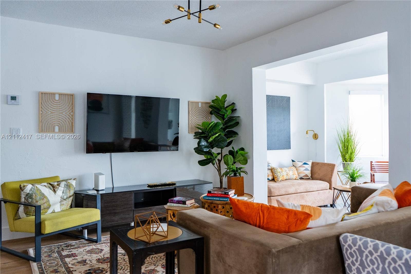 Open-concept living space featuring a geometric multi-arm ceiling fixture, recessed wall niche, and wood-finish flooring