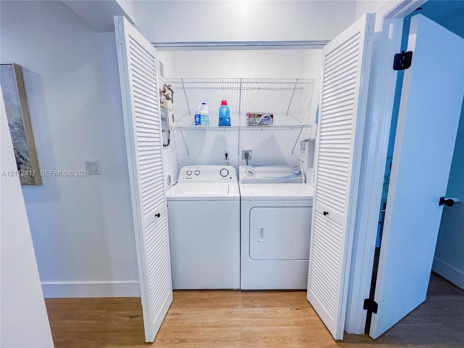Laundry closet featuring louvered bifold doors and built-in wire shelving