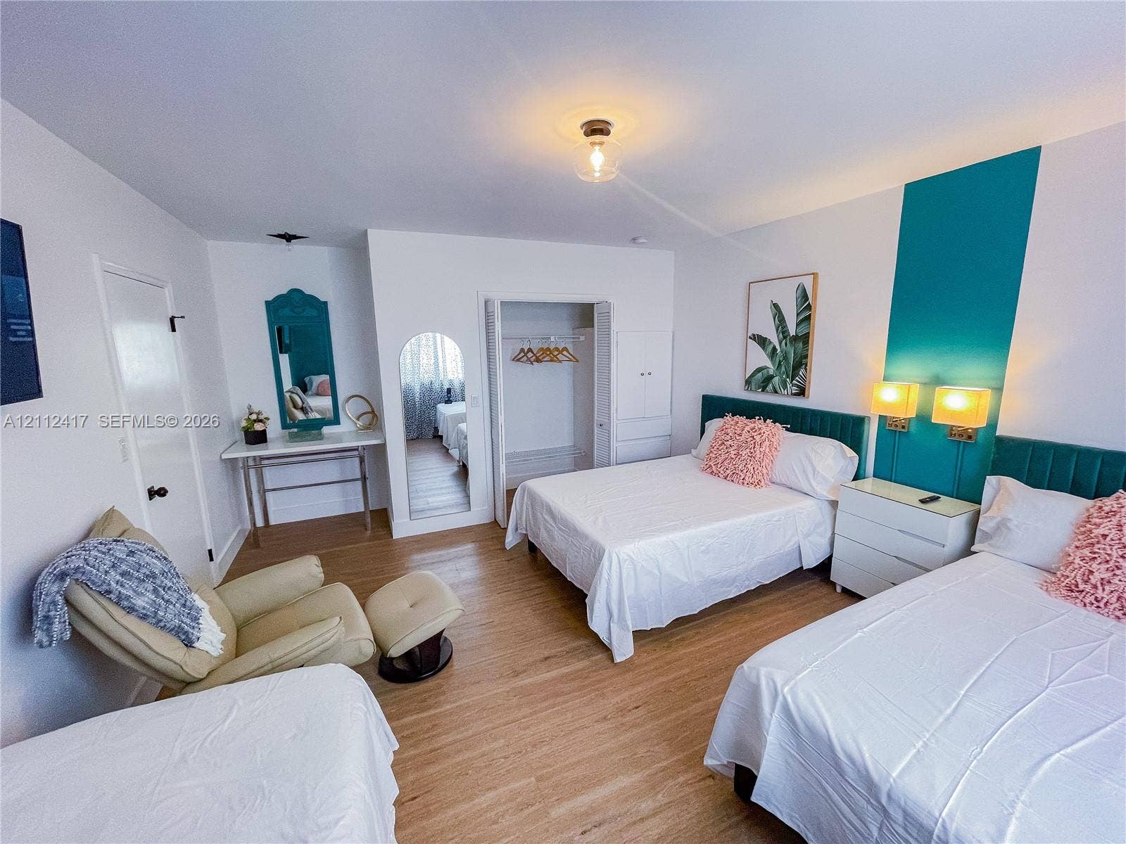 Spacious room featuring wood-finish flooring, built-in shelving, a walk-in closet with integrated storage, and decorative wall-mounted accent panels