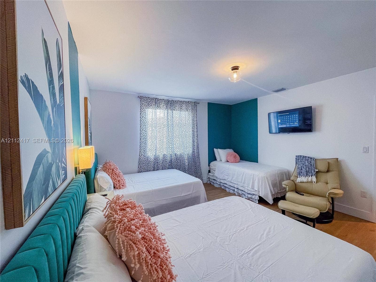 Bedroom featuring wood-finish flooring, accent wall paint, and a central flush-mount light fixture