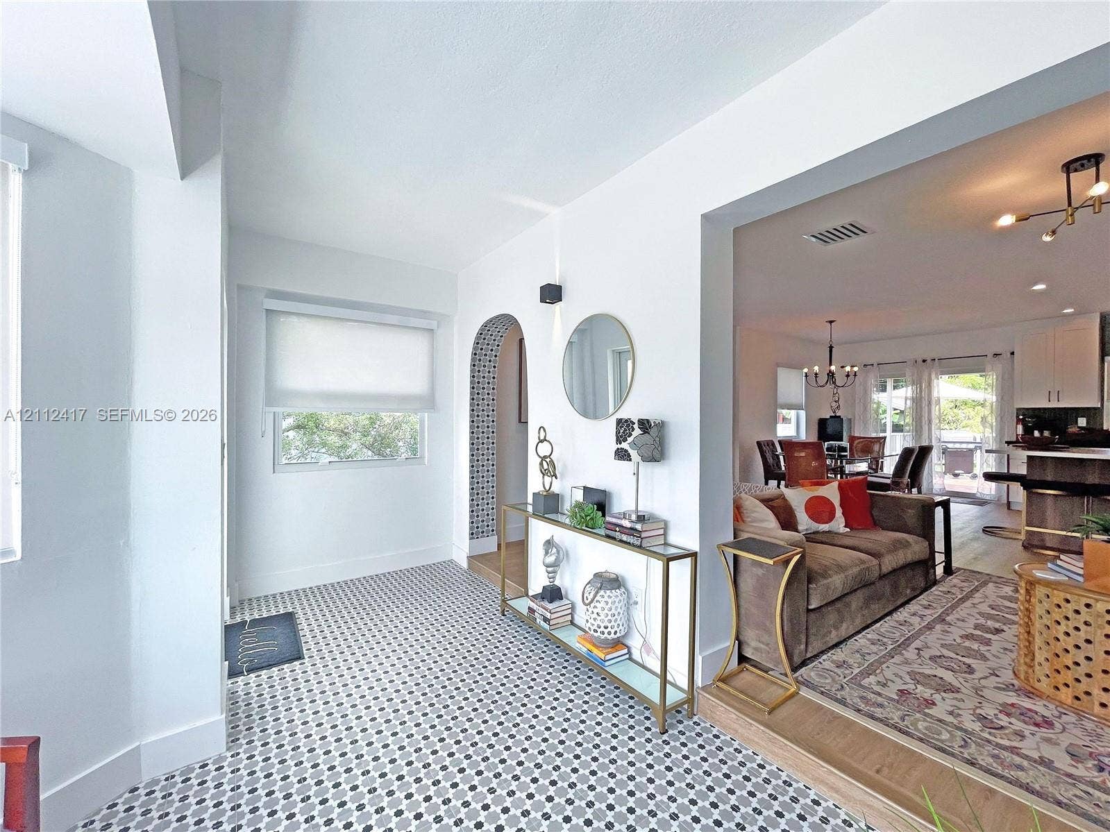 Geometric tile flooring, arched entryway with decorative mosaic tile detailing, and wood-finish flooring