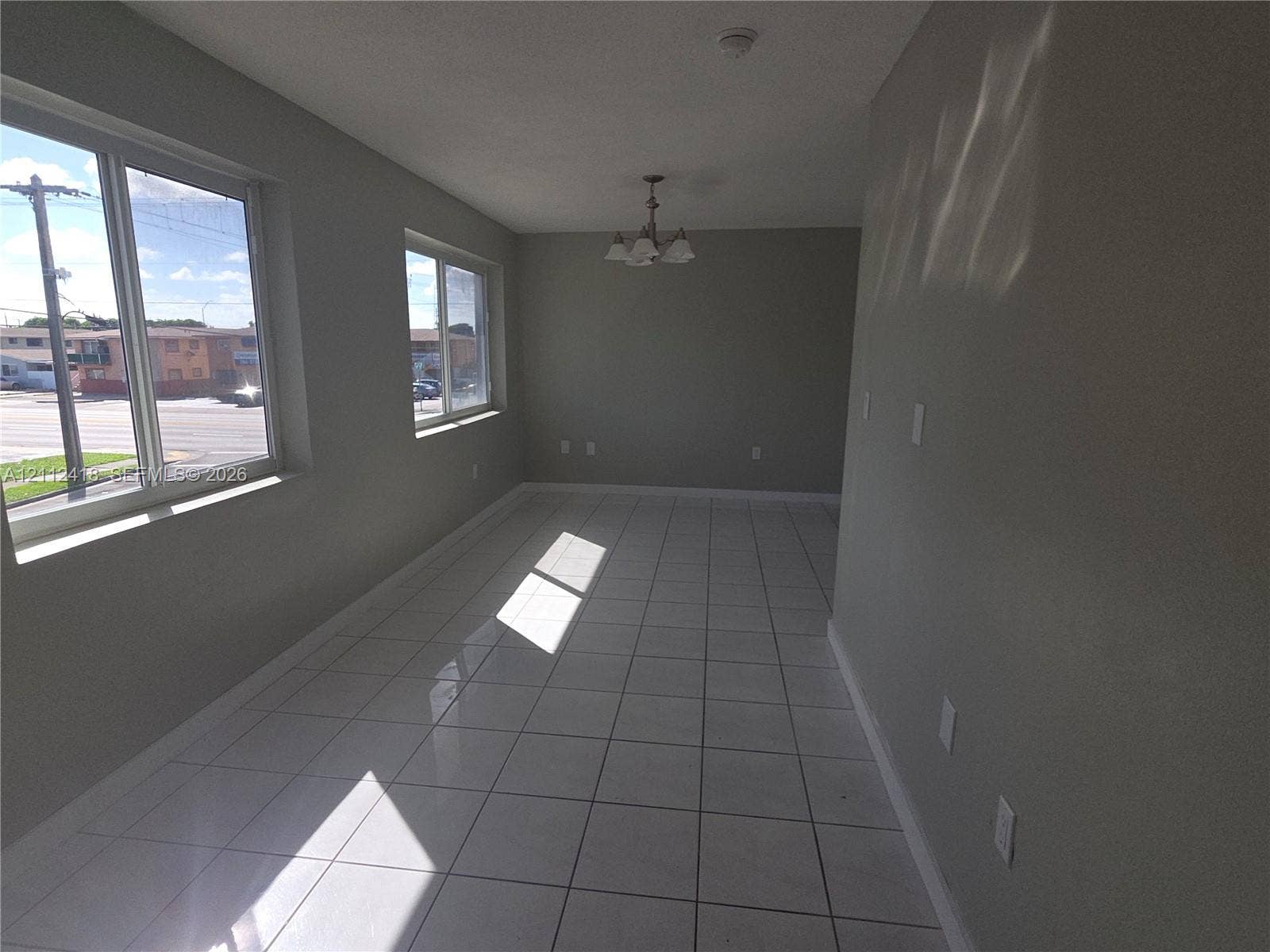 Interior space featuring large-format ceramic tile flooring, neutral wall tones, multi-pane windows, and a traditional tiered ceiling fixture