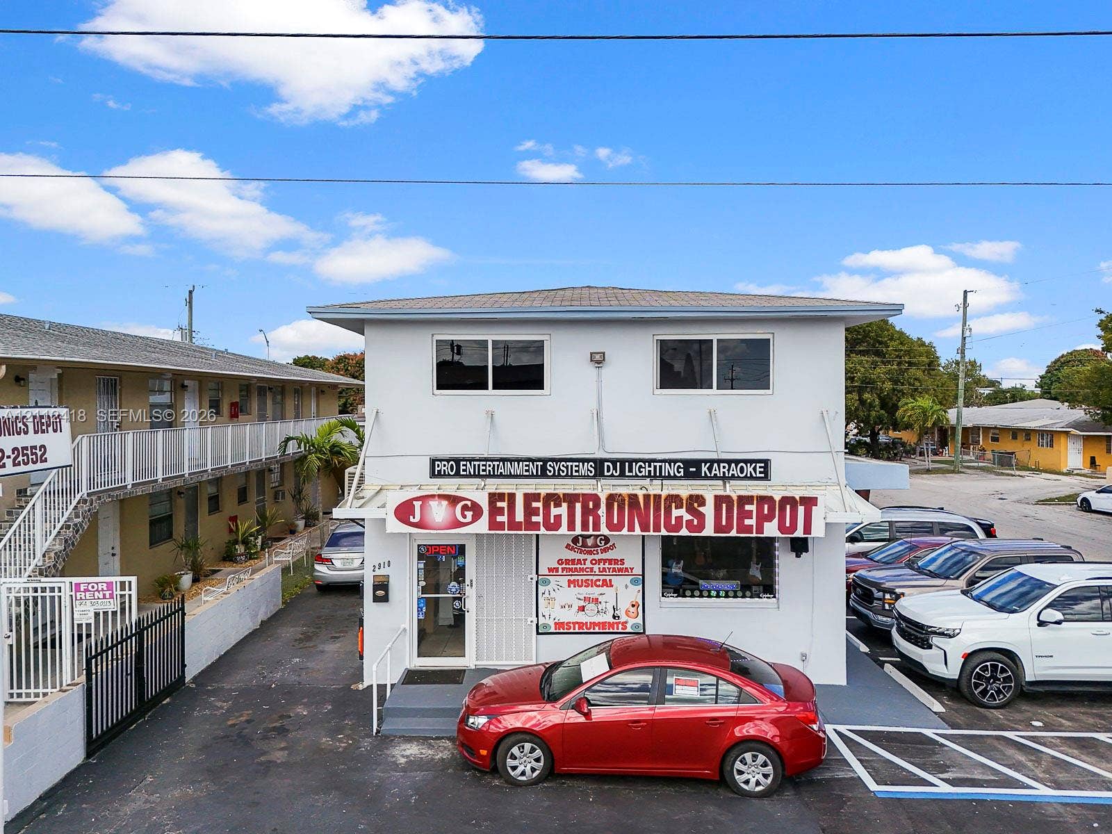 Two-story commercial building featuring a flat roof, concrete block construction, ground-level glass entry, and dedicated asphalt parking area