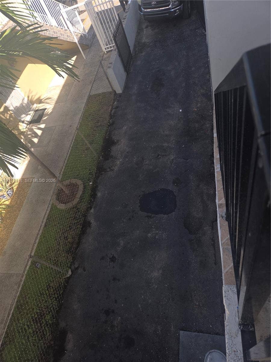 Asphalt driveway featuring 2 parking spaces a chain-link fence
