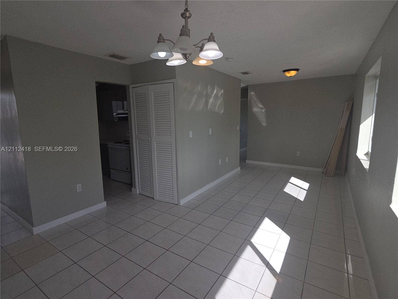 Ceramic tile flooring, five-light brushed nickel chandelier, recessed ceiling lighting, and louvered double-door closet