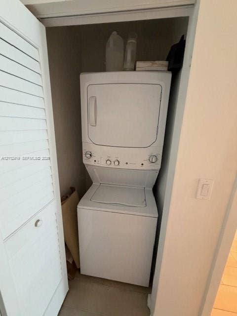 Laundry closet featuring a white stacked washer and dryer unit concealed behind a louvered bi-fold door