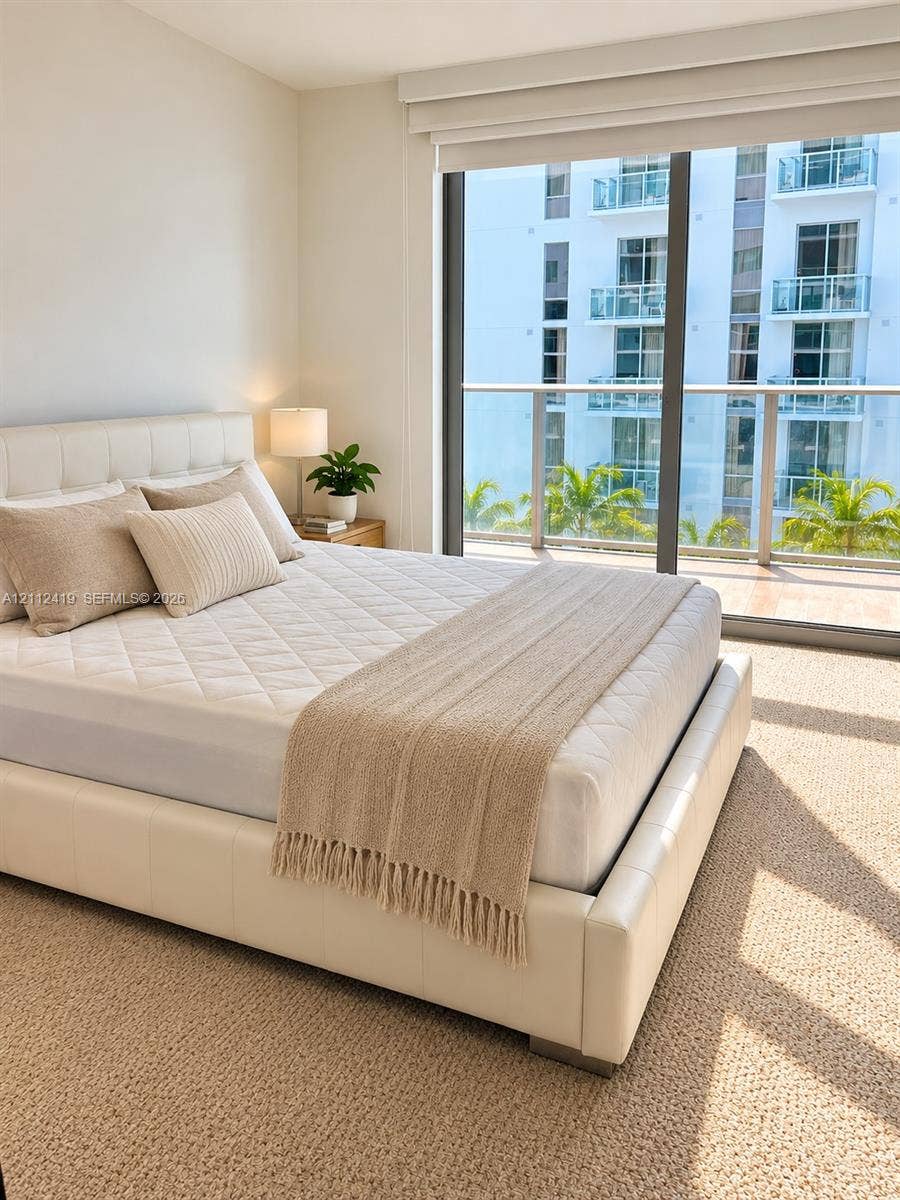 Floor-to-ceiling windows featuring a glass-railing balcony, neutral wall-to-wall carpeting, and integrated window treatments