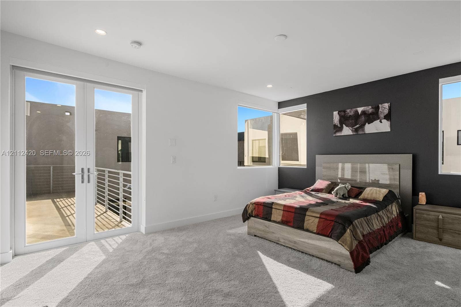 10054 NW 76th Terrace, Doral, FL 33178 Interior space featuring recessed lighting, carpeted flooring, a dark accent wall, and double-glass doors opening to an exterior balcony with a metal railing