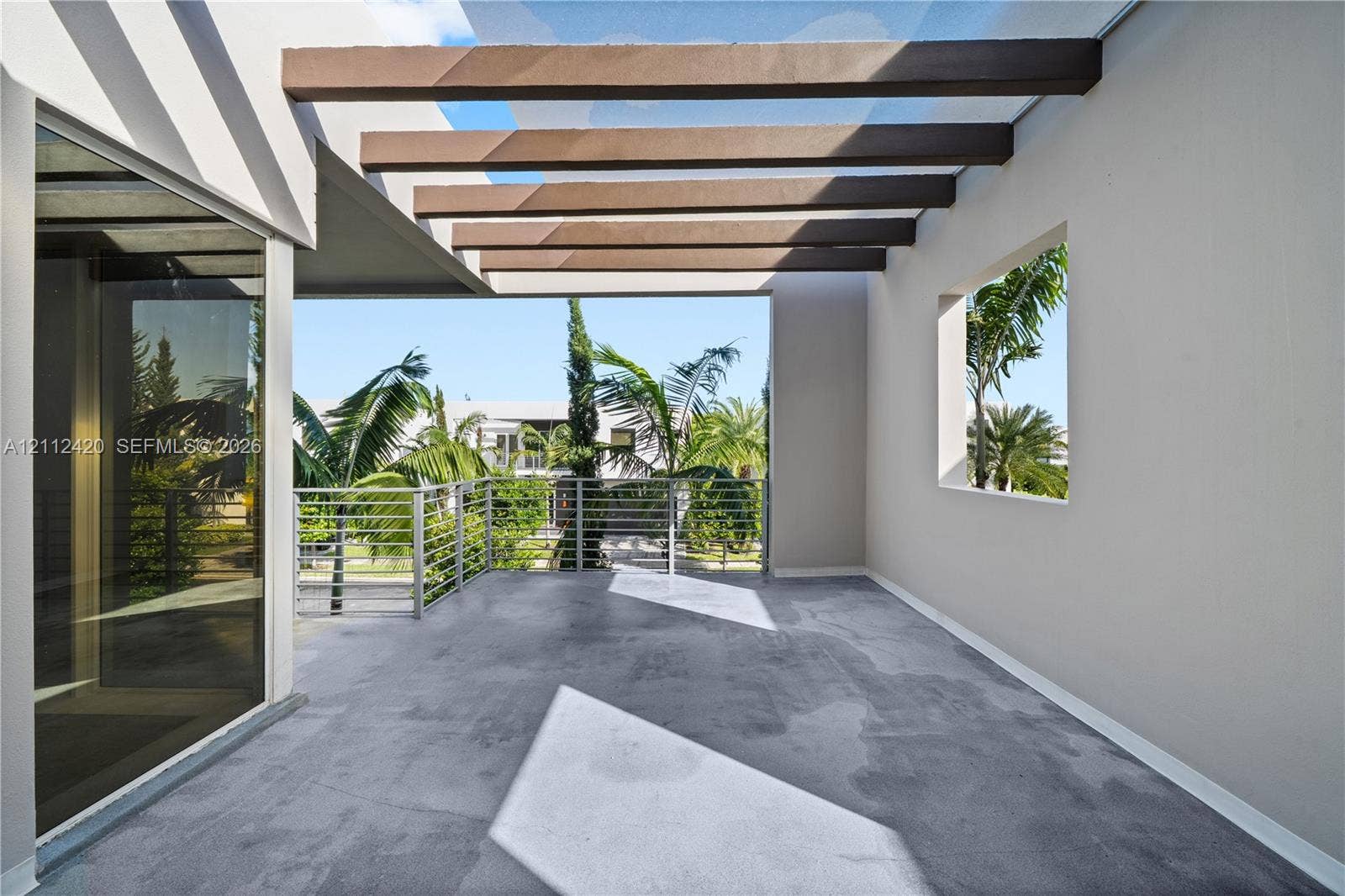 10054 NW 76th Terrace, Doral, FL 33178 Covered balcony featuring exposed wooden ceiling beams, concrete flooring, and metal horizontal railings