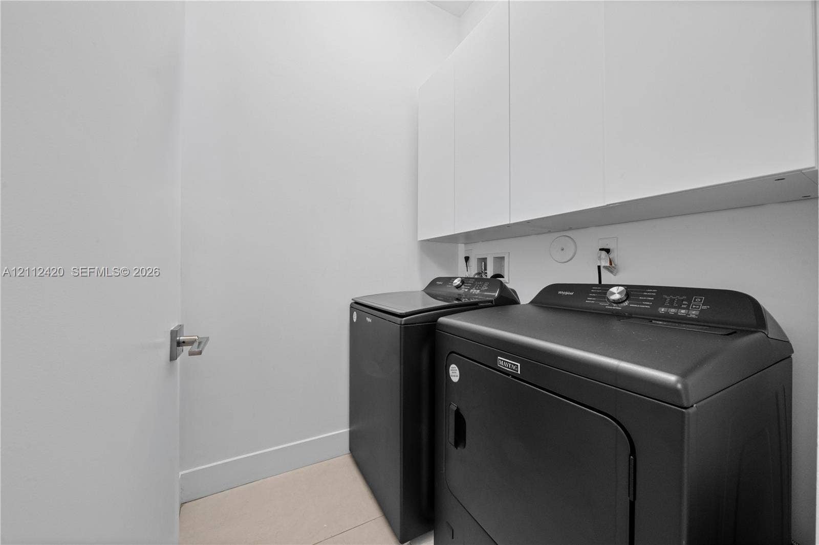10054 NW 76th Terrace, Doral, FL 33178 Dedicated laundry area featuring white wall-mounted cabinetry and light-toned tile flooring