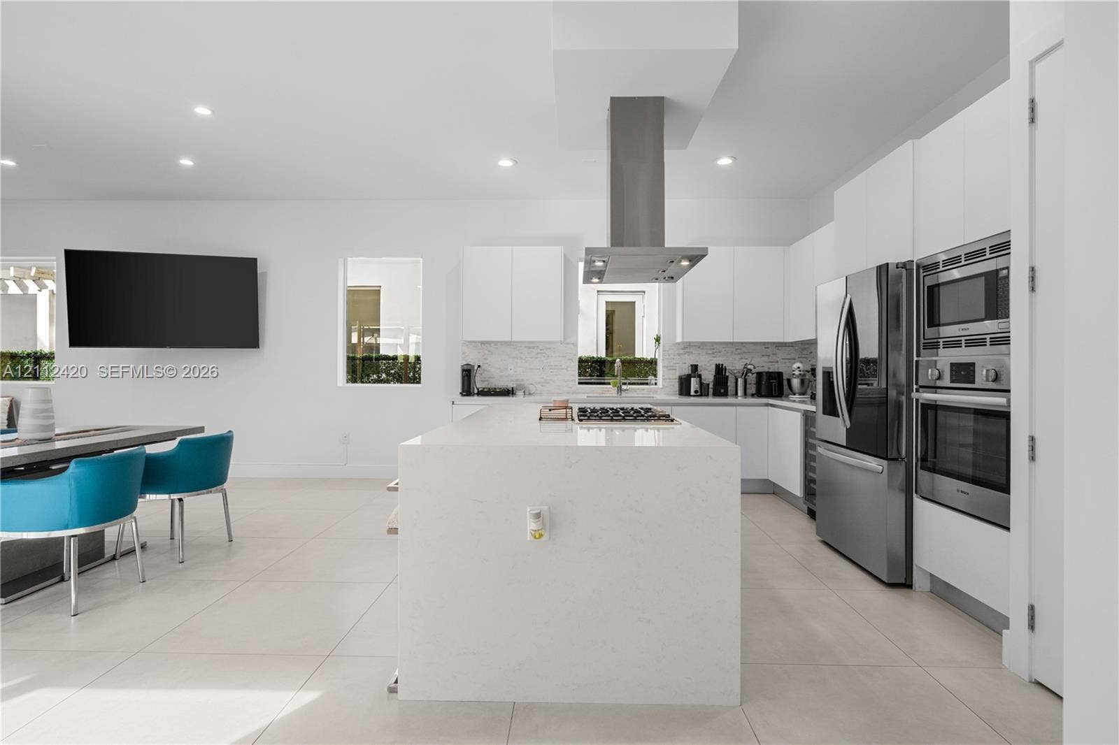 10054 NW 76th Terrace, Doral, FL 33178 Kitchen featuring a central island with a solid surface countertop, stainless steel appliances, built-in double wall ovens, a stainless steel range hood, and flat-panel cabinetry