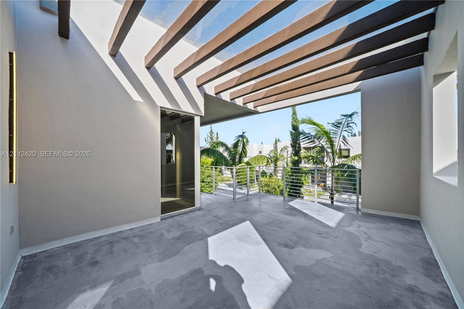 10054 NW 76th Terrace, Doral, FL 33178 Covered balcony featuring a wood-beam pergola, concrete flooring, vertical accent lighting, and a metal railing