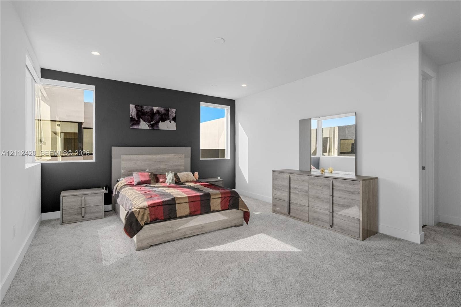 10054 NW 76th Terrace, Doral, FL 33178 Neutral-toned carpeting, high-contrast dark accent wall, recessed lighting, and large windows providing natural illumination