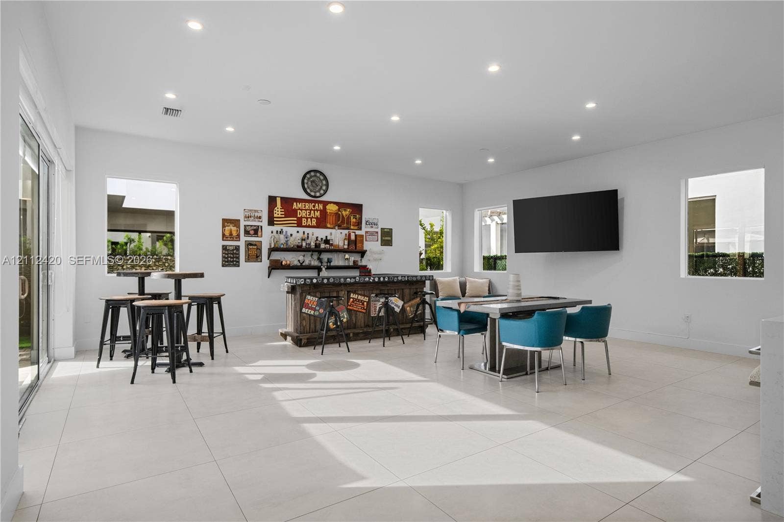 10054 NW 76th Terrace, Doral, FL 33178 Spacious room featuring large-format tile flooring, recessed lighting, and a built-in bar area with wood cabinetry