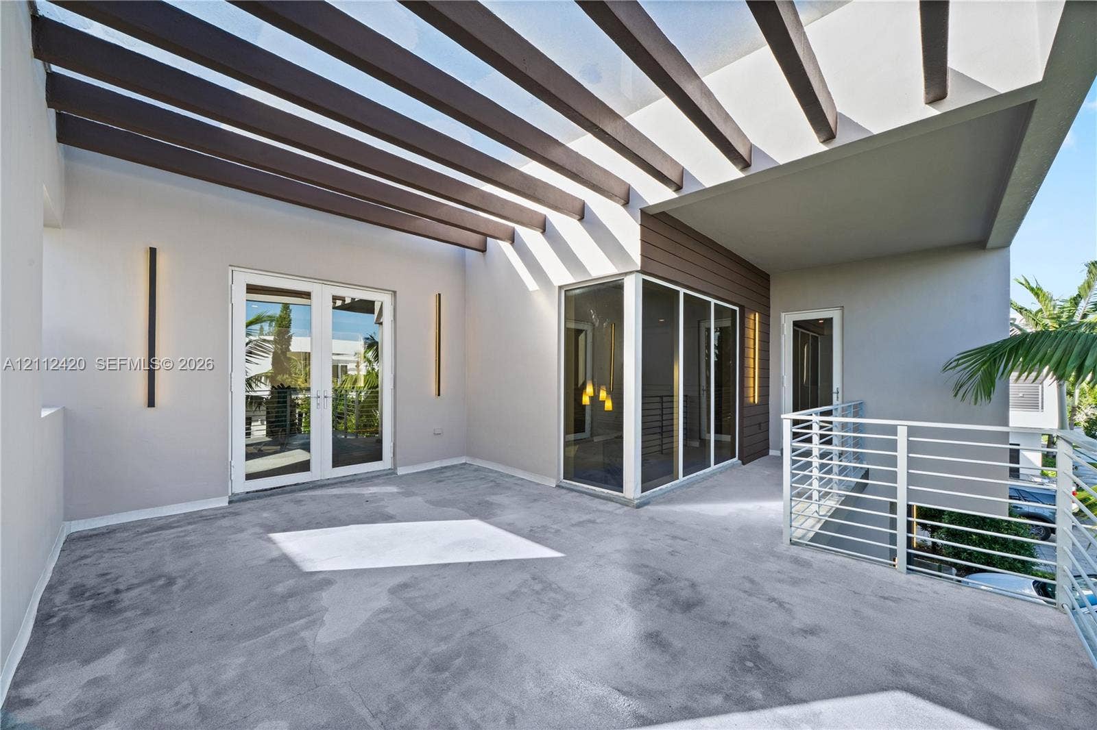 10054 NW 76th Terrace, Doral, FL 33178 Covered terrace featuring a decorative pergola, concrete flooring, exterior wall-mounted lighting, and horizontal metal railings