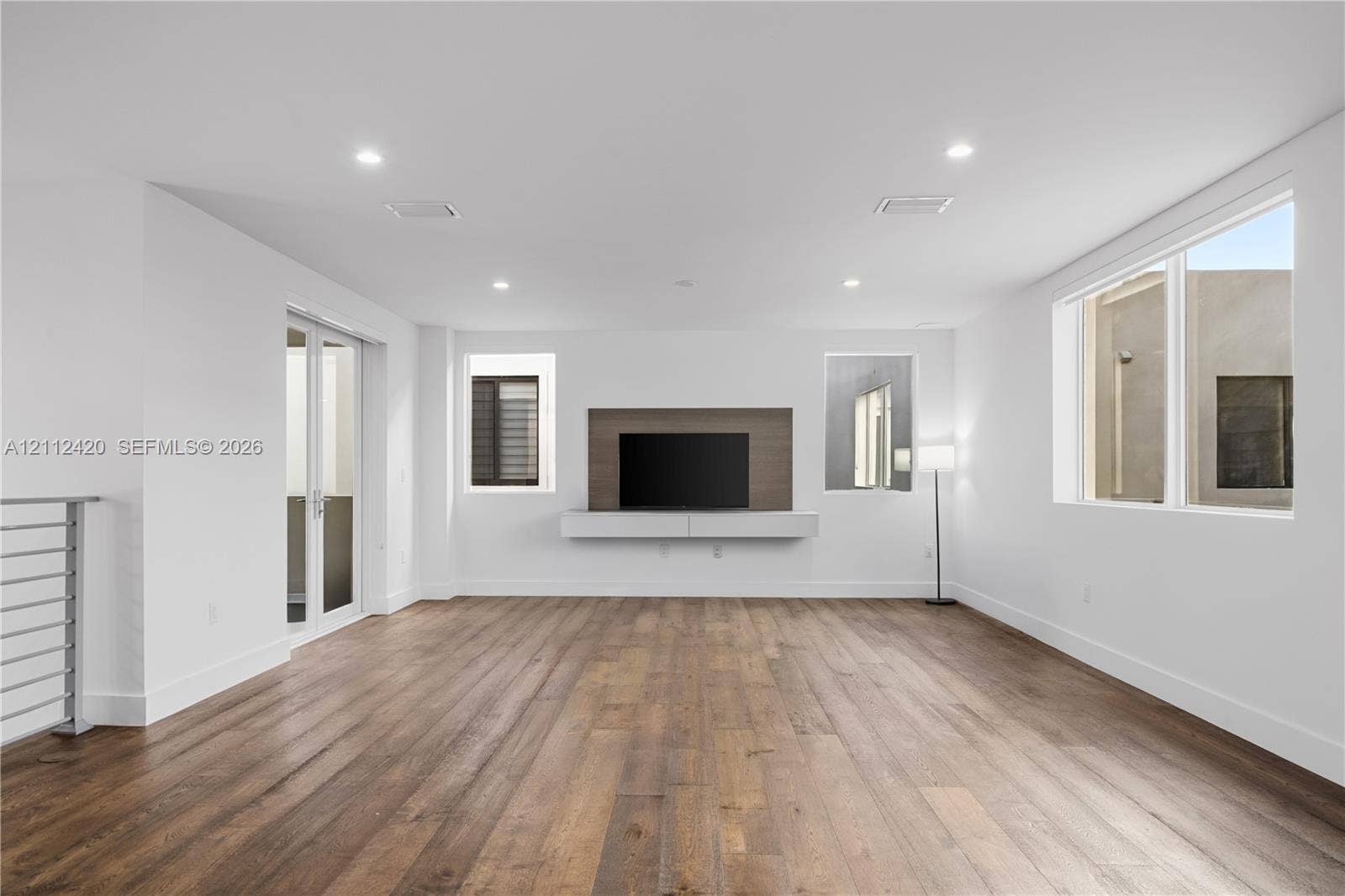 10054 NW 76th Terrace, Doral, FL 33178 Spacious interior featuring wood-finish flooring, recessed lighting, and a custom built-in wall unit with an integrated media backdrop