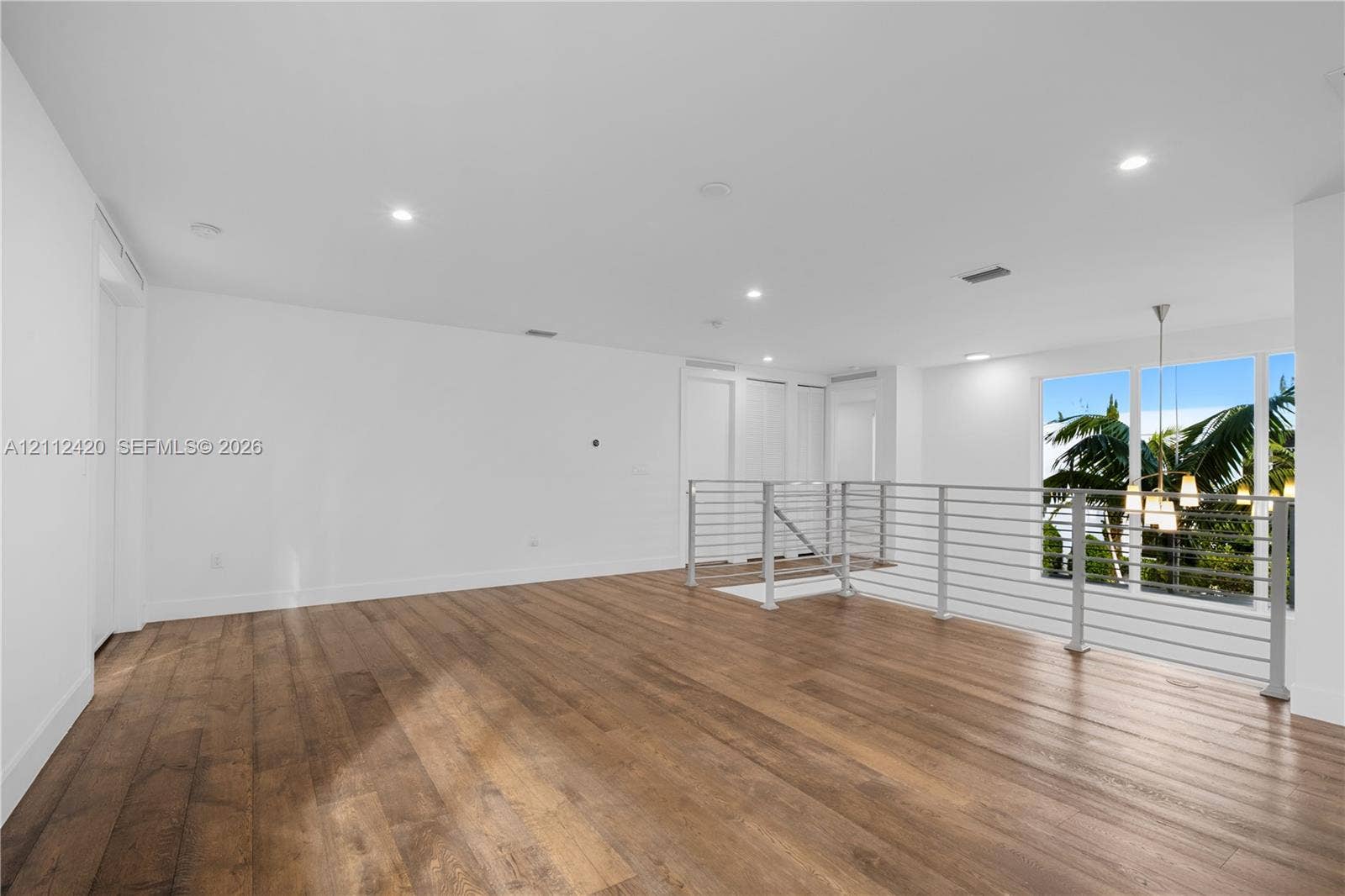 10054 NW 76th Terrace, Doral, FL 33178 Open-concept area featuring wood-finish flooring, recessed lighting, and a metal horizontal-bar railing