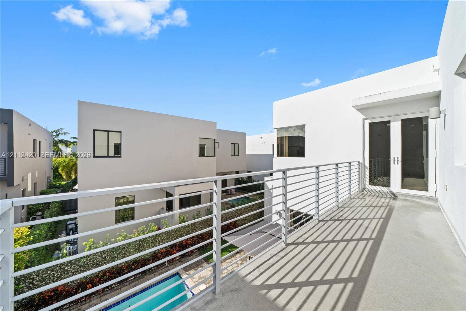 10054 NW 76th Terrace, Doral, FL 33178 Modern balcony featuring sleek metal railing, smooth concrete flooring, and double-glass entry doors