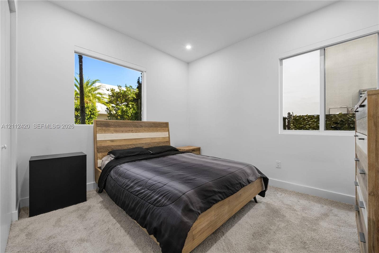 10054 NW 76th Terrace, Doral, FL 33178 Neutral interior space featuring high-pile carpeting, smooth-finish walls, recessed ceiling lighting, and dual windows with exterior palm tree exposure