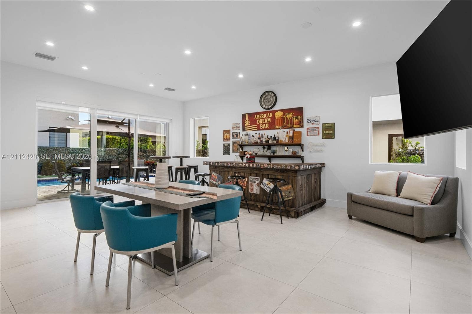 10054 NW 76th Terrace, Doral, FL 33178 Open-concept space featuring large-format tile flooring, recessed lighting, a built-in wooden bar, and sliding glass doors