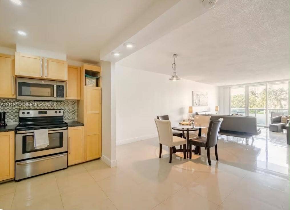 Kitchen featuring light-finish cabinetry, stainless steel appliances, and a decorative tile backsplash, paired with large-format tile flooring and recessed lighting