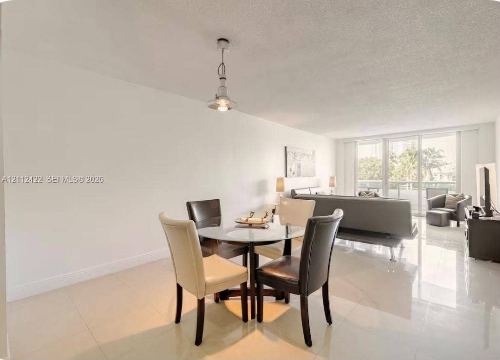 Open-concept living space featuring high-gloss tile flooring, floor-to-ceiling glass sliding doors, and a decorative pendant light fixture