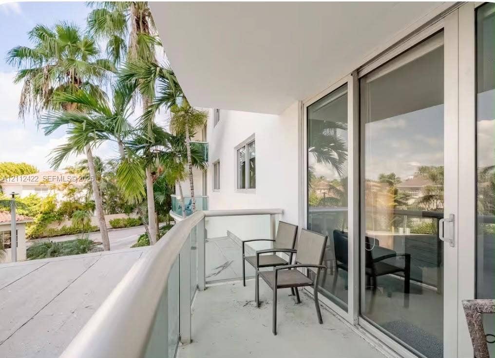 Private balcony featuring a concrete floor, glass panel railing with a metal handrail, and large sliding glass door access