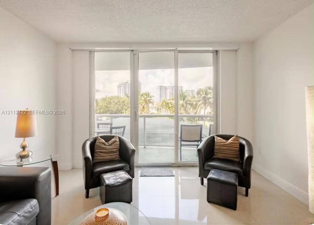Interior space with large-format tile flooring, neutral walls, and a glass-paneled sliding door providing access to an exterior balcony