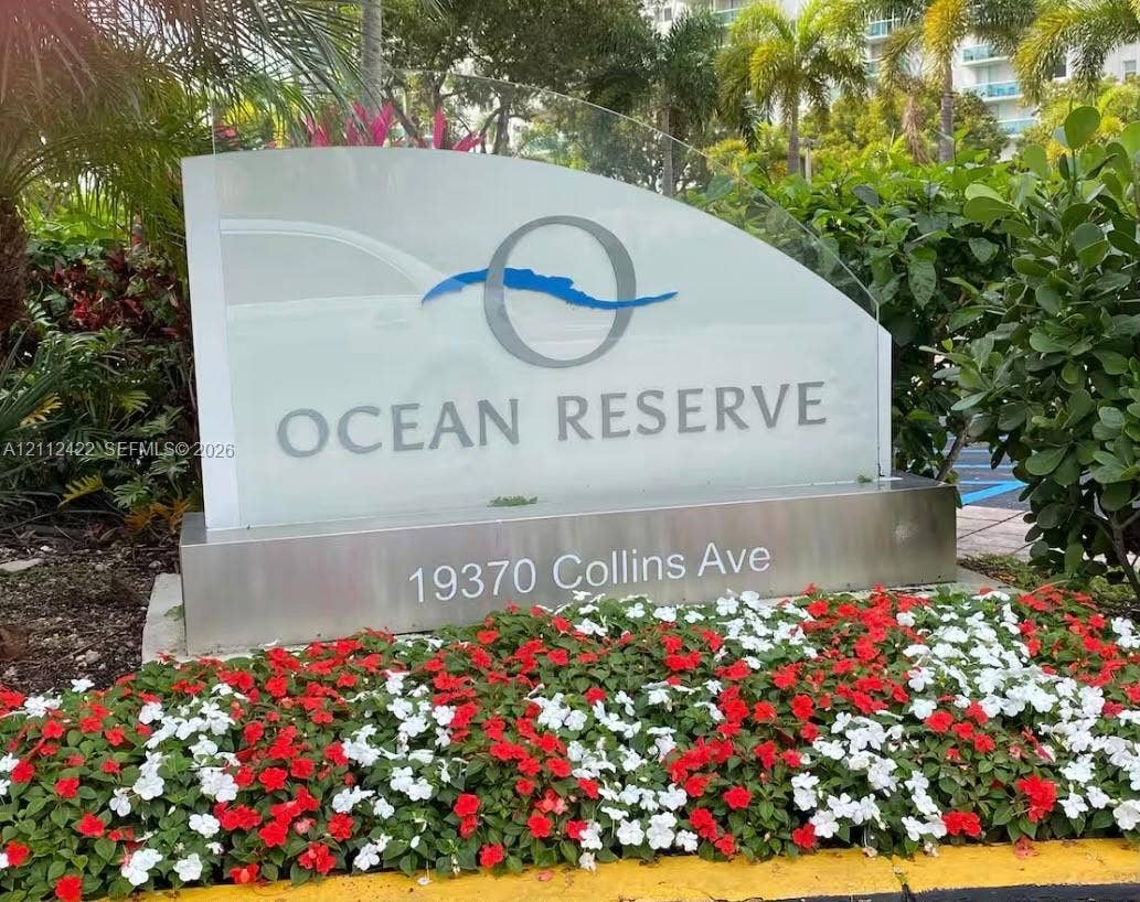 Ocean Reserve monument signage featuring a glass-panel display with brushed-metal base and surrounding manicured garden beds