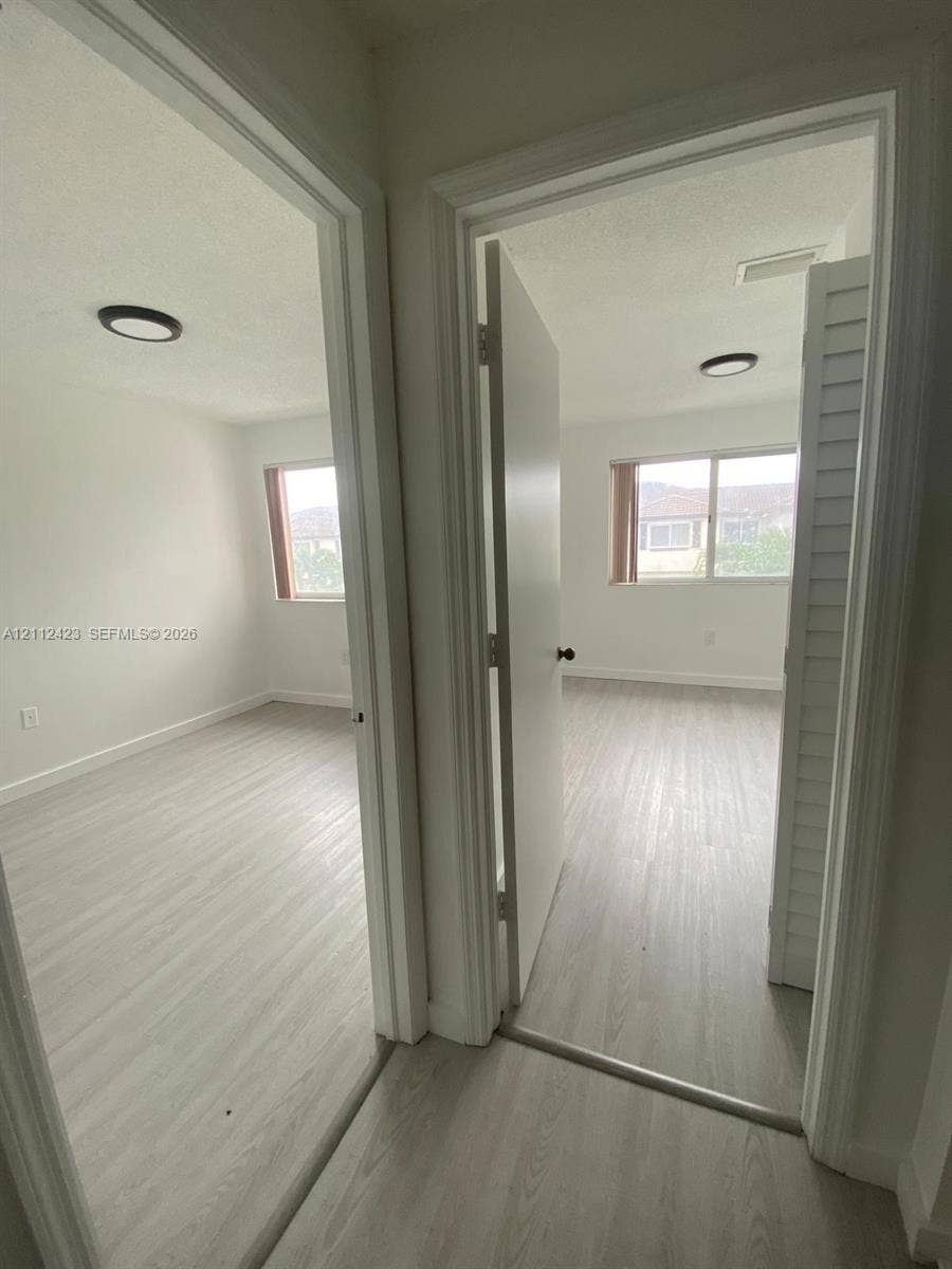 8555 SW 152nd Avenue, #104, Miami, FL 33193 Rooms featuring wood-finish flooring, sliding windows, and flush-mount lighting fixtures, including a room with bi-fold closet doors