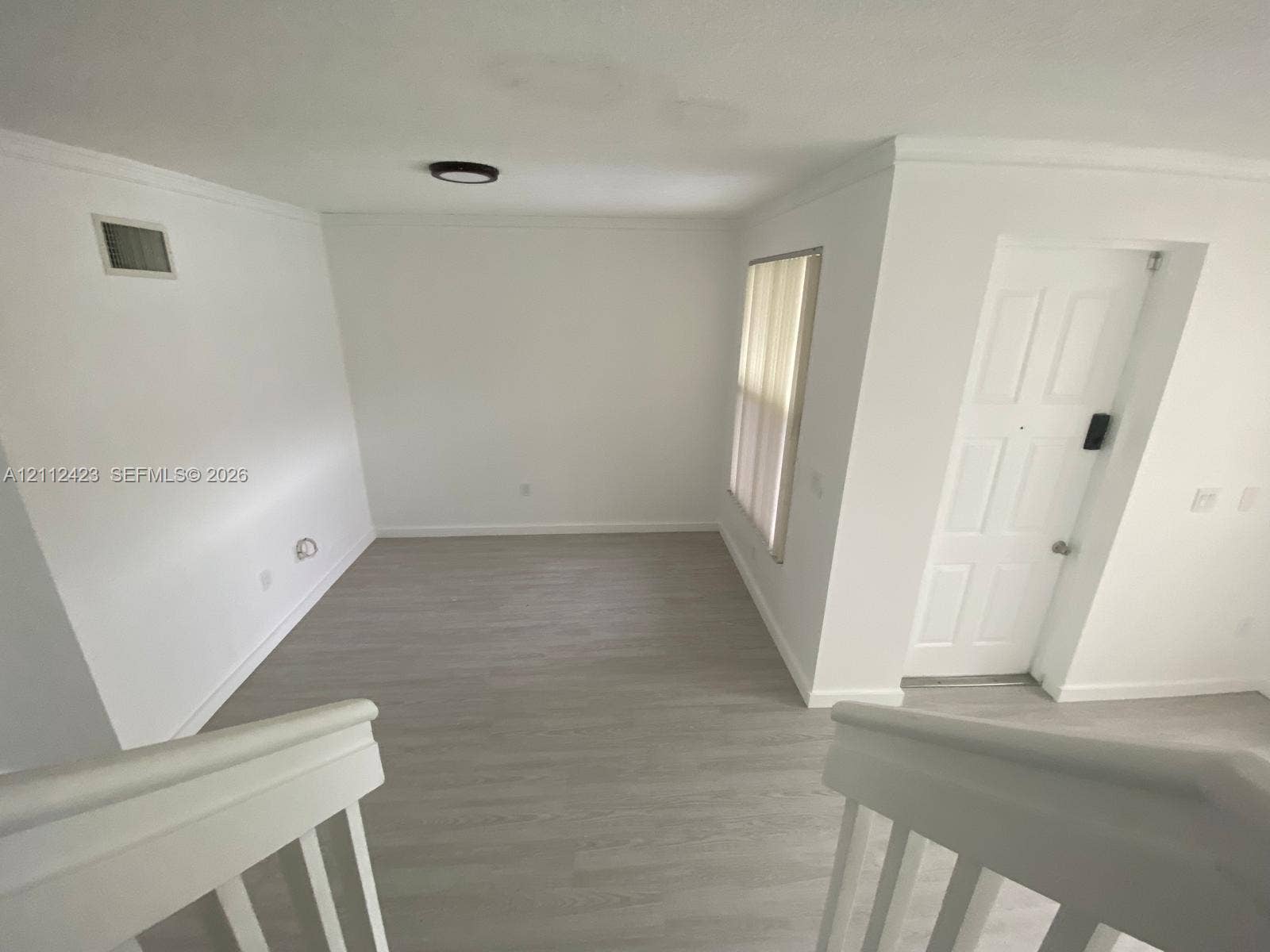 8555 SW 152nd Avenue, #104, Miami, FL 33193 Interior space featuring wood-finish flooring, a six-panel door, crown molding, and a minimalist flush-mount ceiling light fixture