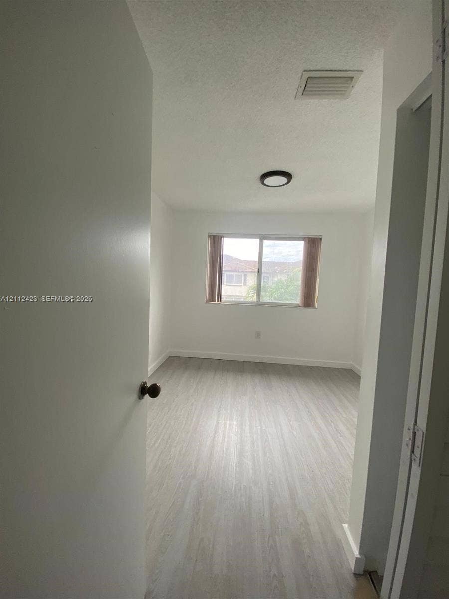 8555 SW 152nd Avenue, #104, Miami, FL 33193 Interior room featuring neutral wall finishes, wood-finish flooring, a flush-mount circular light fixture, and a dual-pane sliding window